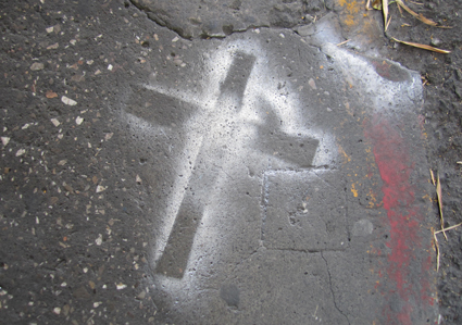 spray-painted cross on the road