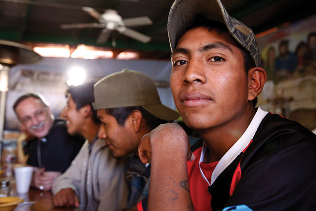Across the border in Nogales, Sonora, Mexico, Kino Border Initiative operates an aid center for deported migrants. Here a group of young men awaits dinner while chatting with members of a visiting delegation of U.S. bishops. 
