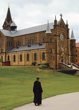 priest walking in front of Saint Meinrad Archabbey