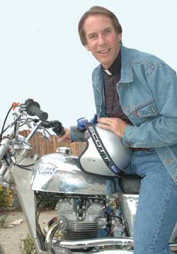AUJOURD'HUI, l’abbé Paul Boudreau accomplit son ministère dans une paroisse à Beaumont en Californie.  Il  arrive  parfois aux évènements paroissiaux sur sa vieille moto de course reconstituée!