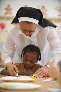 Sister Lucia Quesada helps a student add color to her masterpiece at the Mt. Providence Child Development Center. 