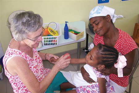 Sister Lorraine Malo, C.S.J. has worked as a physical therapist in Haiti for many years. She rode out the earthquake and its aftermath and today continues to provide service. Above she works with Mylove and her mother in a therapy session.