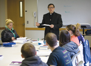 Holy Cross Father George A. Piggford, C.S.C., director of the Honors Program and associate professor at Stonehill College, Easton, Massachusetts, in the classroom with students.