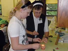 Sister Annette Kurey, O.S.F. of the Franciscan Sisters of Christian Charity in Manitowoc, Wisconsin helps a summer camper with her prayer beads.