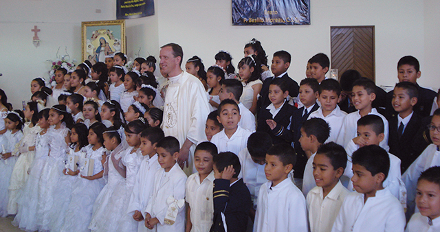 tHerman takes time for a “photo op” with kids at their First Communion.