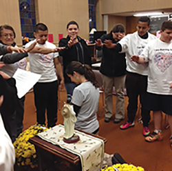 Parra kneels to receive a blessing before she runs a marathon.