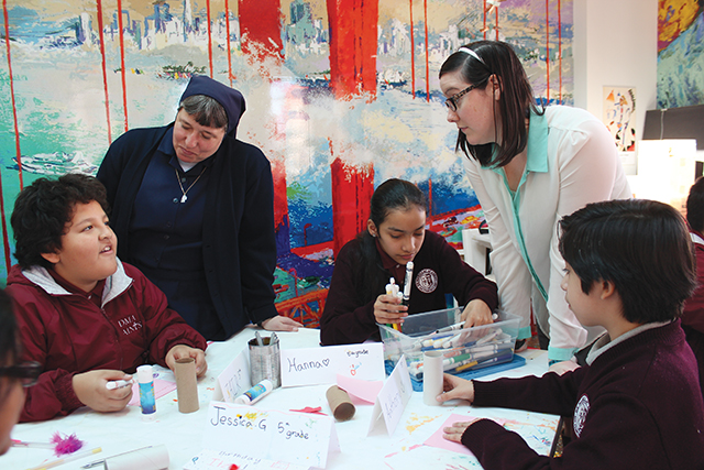 Sister Lisa Laguna, D.C. and a volunteer help fifth-graders with their art projects. 