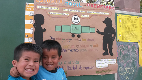 Two children have big smiles at Escuela Móvil. 
