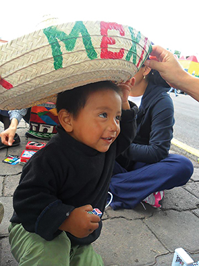 Volunteers surprise one of their youngest visitors with a traditional Mexican sombrero.