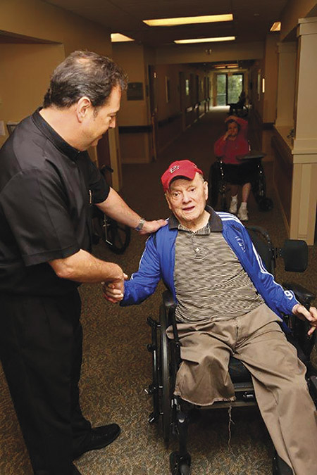 Brother Tom Klein, C.F.A. speaks to a resident in a nursing home run by his community, the Alexian Brothers.