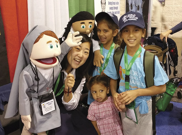 Lee has fun with puppets and children at a Salesian Sisters outreach display.