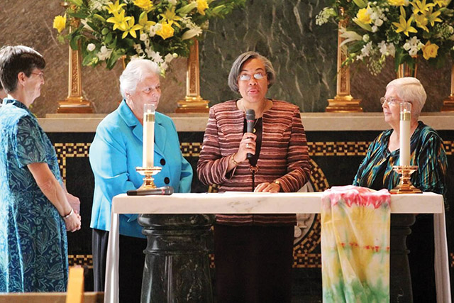Sister Jackie Nedd, R.S.M. is pictured here at the microphone taking her final vows with (from left) Sisters Marguerite Pessagno, R.S.M., her vocation minister; Mid-Atlantic president Patricia Vetrano, R.S.M.; and Institute president Patricia McDermott, R.S.M.