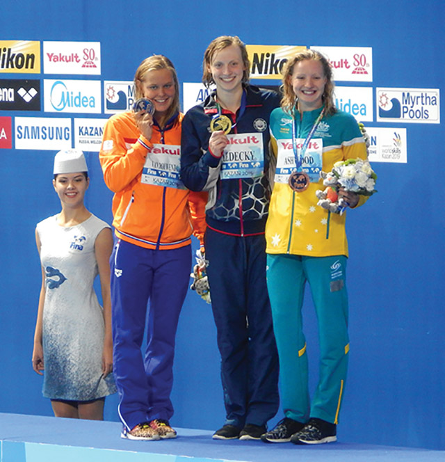 Swimming Olympic gold medalist Katie Ledecky (center) receives an award at an international competition.