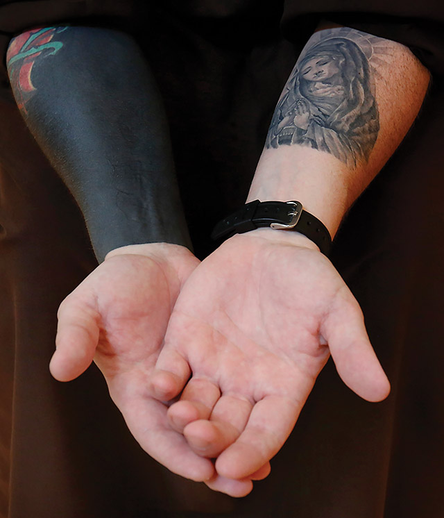 Father M.J. Groark, O.F.M.Cap. shows his tattooed arms