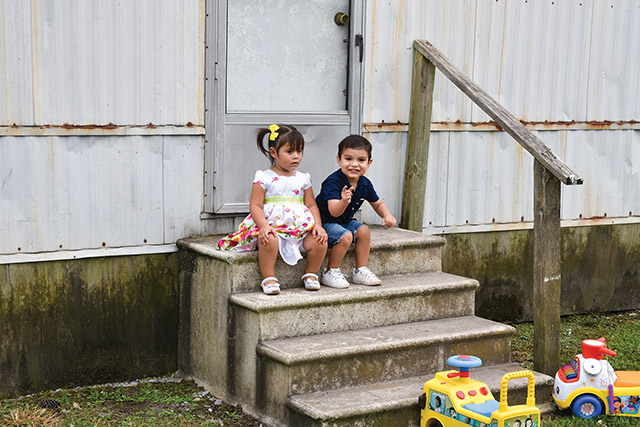 Small children sit on the steps of a home