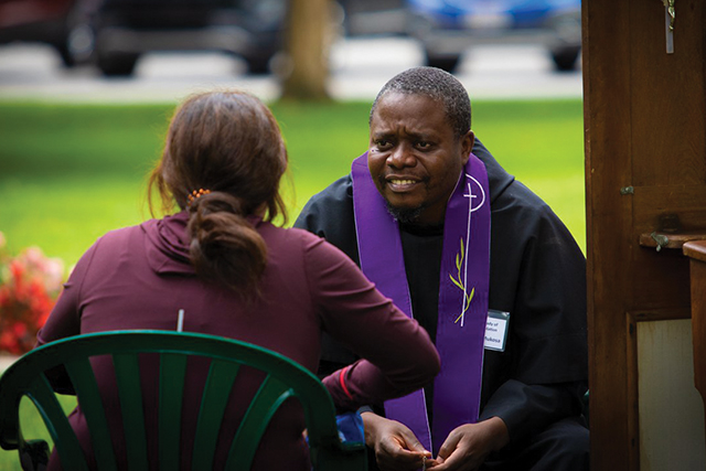 Friar Andrew Mukosa, O.F.M.Conv. of Zambia, who offers mission appeals in the summer, lends a listening ear to a pilgrim visiting the Basilica and National Shrine of Our Lady of Consolation in Carey, Ohio.