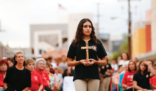 During the Offertory procession at a border Mass in Nogales, a girl carries a cross to remember the migrants who have died in the desert. 
