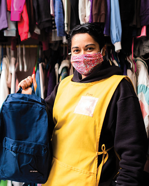 Sister Josefina “Pina” Bejarano Padilla, M.E., of Kino Border Initiative, holds a backpack in front of racks of donated clothing that will be given to migrants.