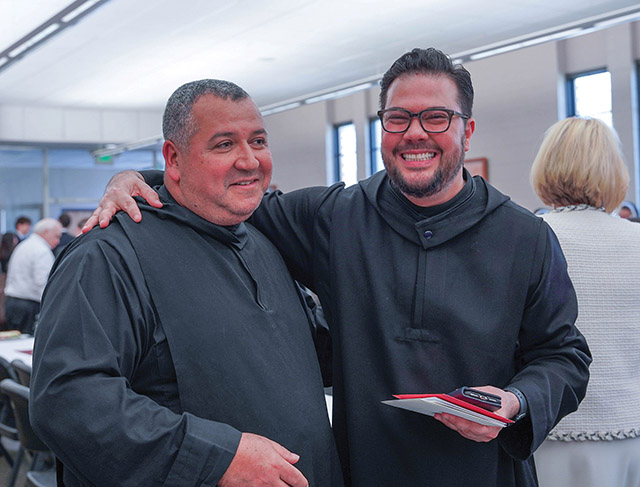 These two monks, Brother Irenaeus Ceballos, O.S.B. and Father Pachomius Alvarado, O.S.B., enjoy a reception with guests after an ordination. 