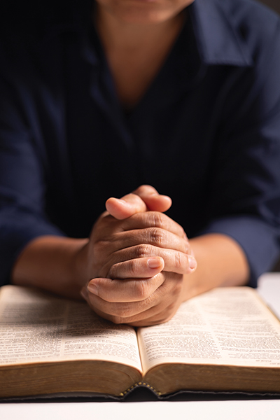 Hands folded in prayer on a Bible