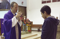 Father John Herman, C.S.C. gives a blessing to one of his flock during a Mass