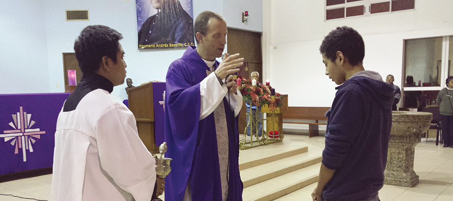 Father John Herman, C.S.C. gives a blessing to one of his flock during a Mass