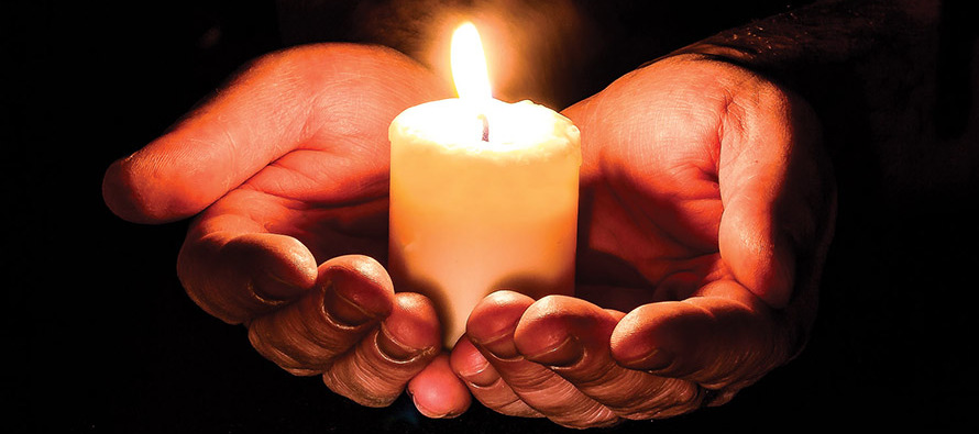Cupped hands holding a candle